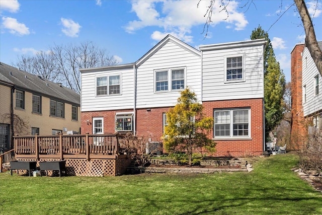 back of property with a yard, a deck, and brick siding