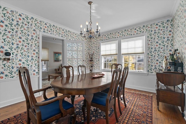 dining space featuring ornamental molding, a chandelier, wood finished floors, and wallpapered walls