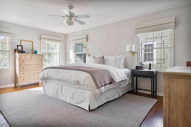 bedroom with wood finished floors, baseboards, and multiple windows