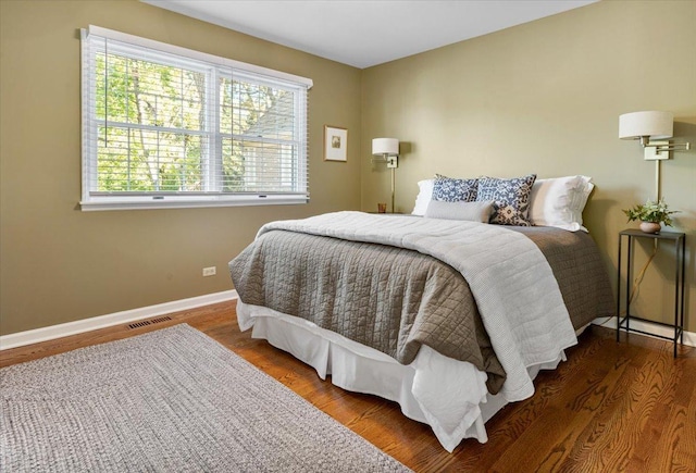 bedroom featuring wood finished floors, visible vents, baseboards, and multiple windows
