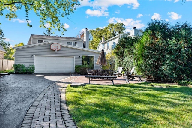 exterior space with a garage, a chimney, aphalt driveway, and a yard