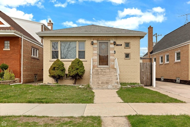 bungalow-style house with brick siding, entry steps, and a front yard