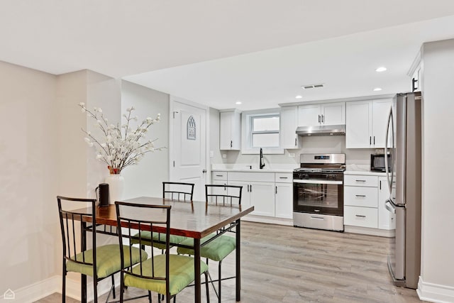kitchen featuring stainless steel appliances, light wood-style floors, under cabinet range hood, visible vents, and light countertops