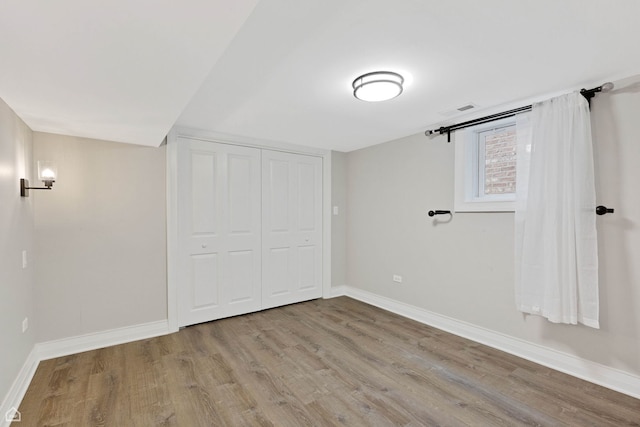 unfurnished bedroom with a closet, visible vents, wood finished floors, and baseboards