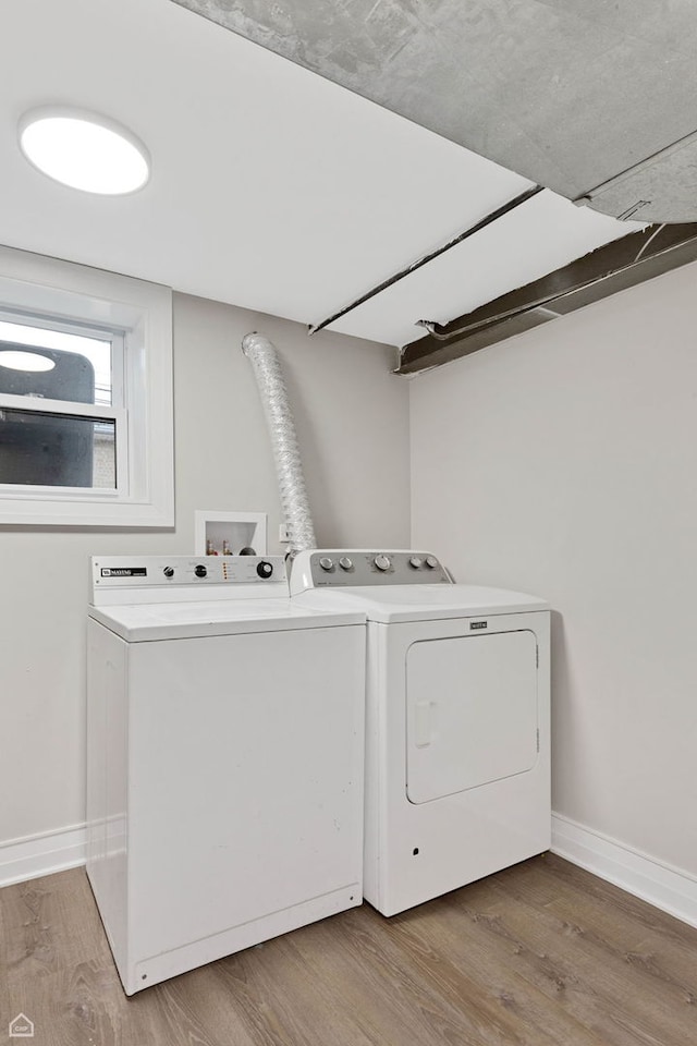 clothes washing area with separate washer and dryer, baseboards, laundry area, and light wood-type flooring