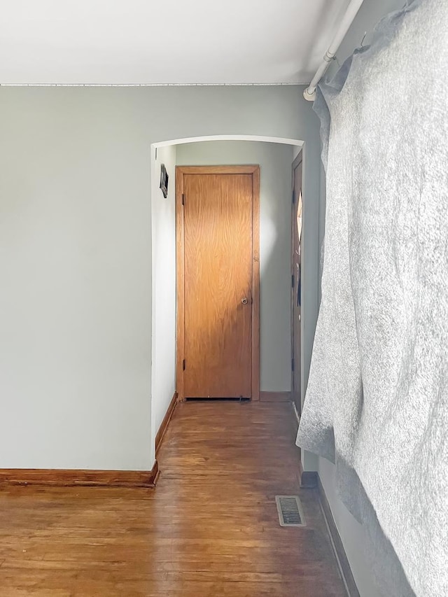 hall with baseboards, visible vents, and wood finished floors