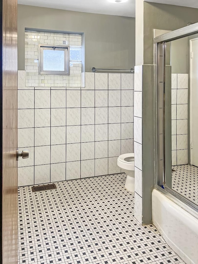 full bathroom with a shower stall, a wainscoted wall, toilet, tile walls, and tile patterned floors