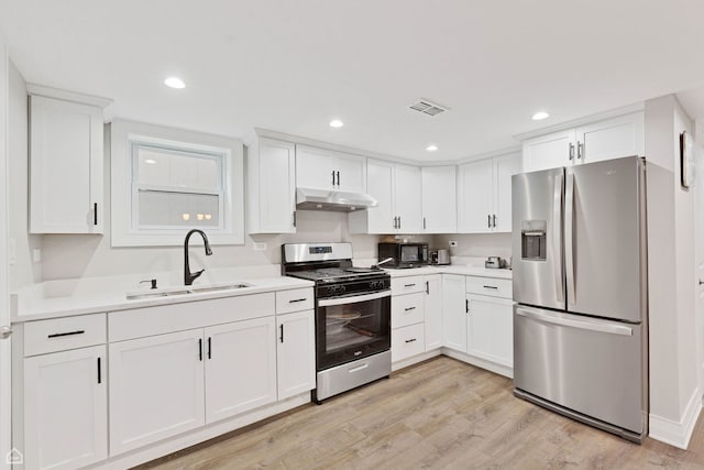 kitchen featuring a sink, stainless steel appliances, under cabinet range hood, white cabinetry, and light wood-style flooring