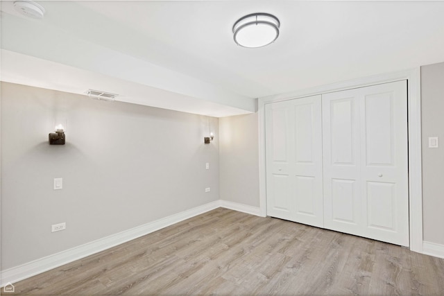 unfurnished bedroom featuring baseboards, visible vents, wood finished floors, and a closet