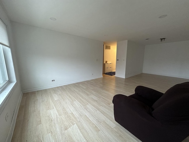 living room with light wood-style flooring, baseboards, and visible vents