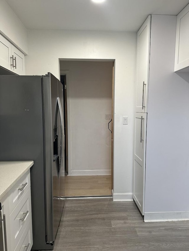 kitchen with stainless steel fridge with ice dispenser, white cabinets, light countertops, and wood finished floors