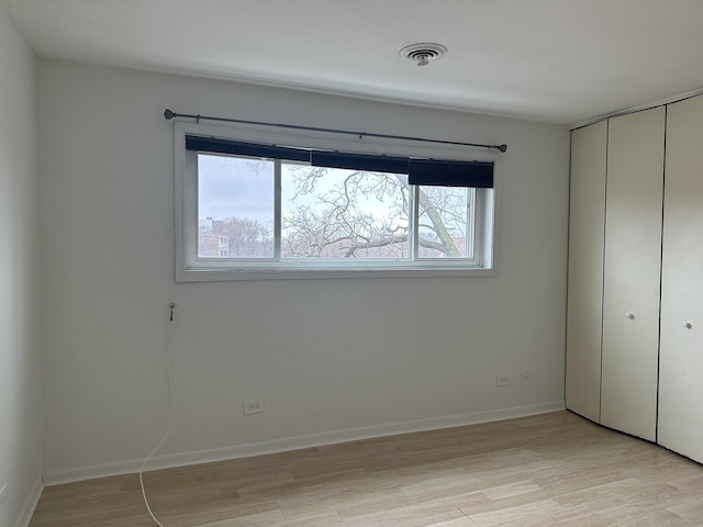 unfurnished bedroom with a closet, multiple windows, and light wood-style floors