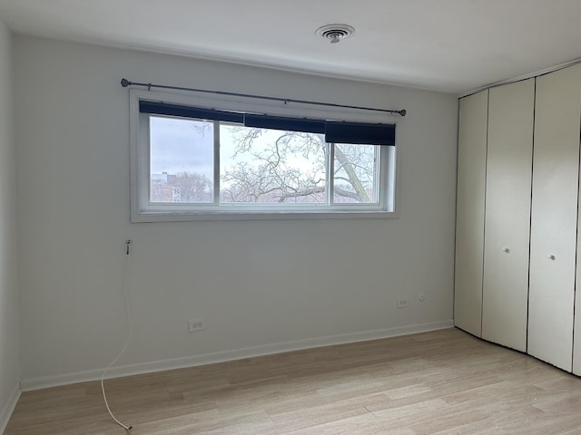 unfurnished bedroom with light wood-type flooring, a closet, baseboards, and visible vents