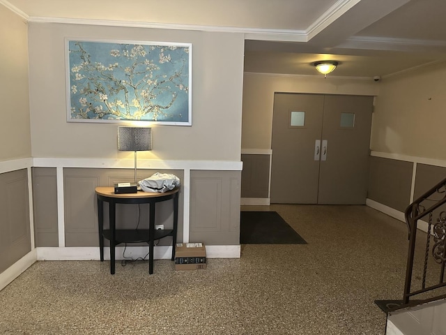entryway featuring a decorative wall, crown molding, and a wainscoted wall