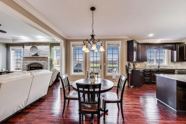 22814 Sara Springs Dr, Frankfort, IL 60423 - dining space with a chandelier, dark wood finished floors, ornamental molding, a stone fireplace, and baseboards