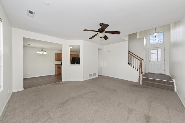 unfurnished living room featuring carpet flooring, baseboards, visible vents, and stairway