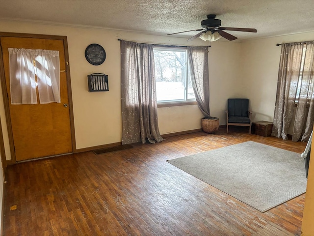 foyer with ceiling fan, a textured ceiling, wood finished floors, and baseboards