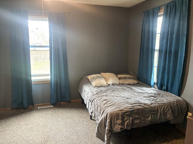 carpeted bedroom with visible vents, multiple windows, and baseboards