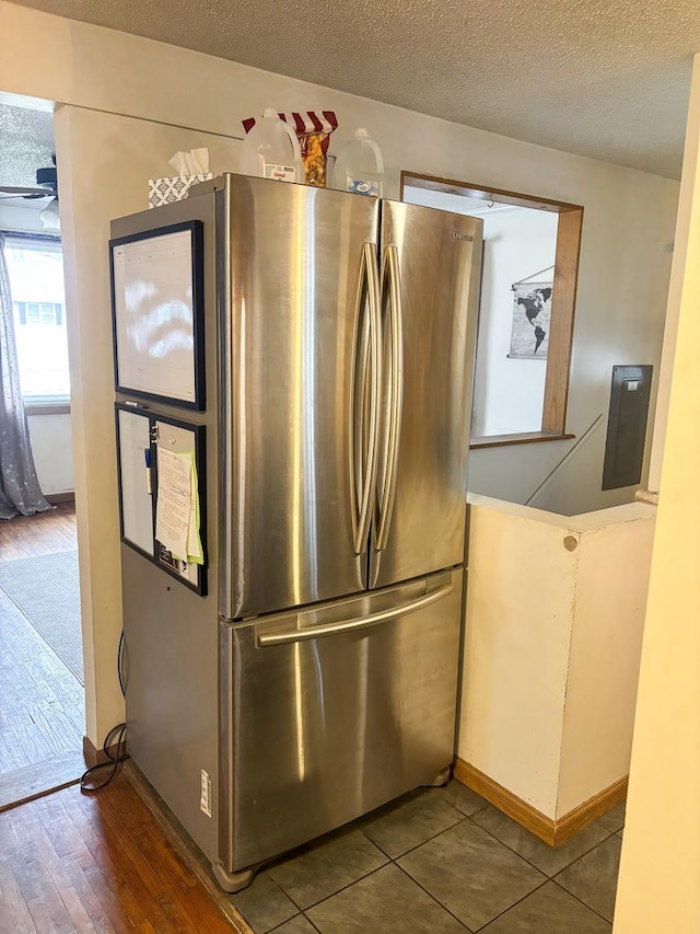interior details with baseboards, electric panel, freestanding refrigerator, a textured ceiling, and wood finished floors