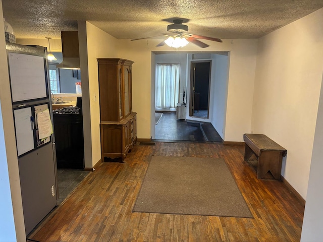 corridor with a textured ceiling, baseboards, and wood finished floors