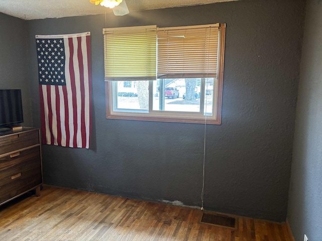interior space featuring a textured wall, visible vents, and wood finished floors