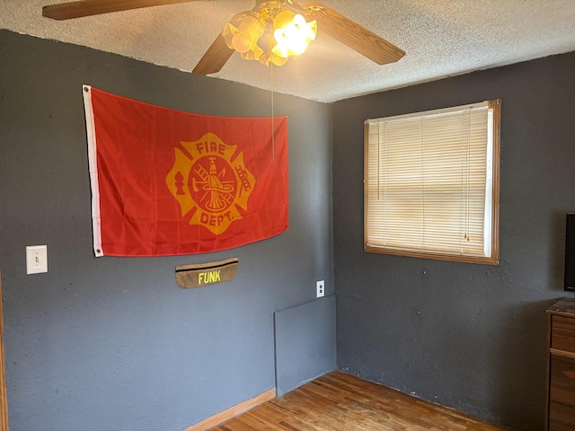 spare room with a ceiling fan, wood finished floors, and a textured ceiling