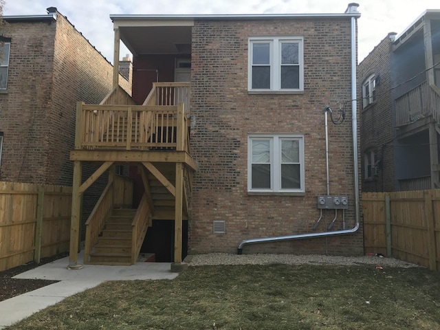 back of house featuring a fenced backyard, stairs, and brick siding