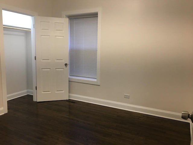 unfurnished bedroom featuring baseboards and dark wood-style floors