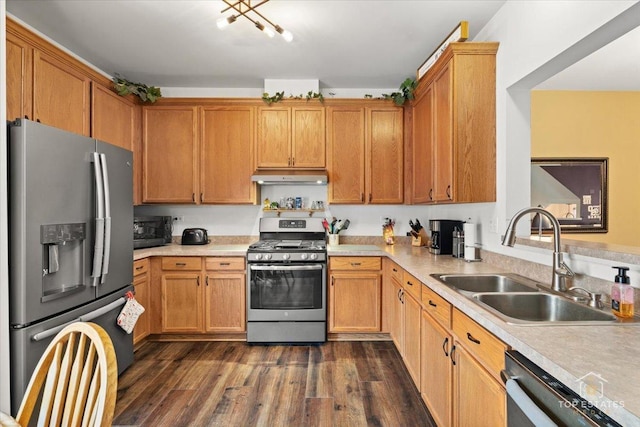 kitchen featuring dark wood-type flooring, under cabinet range hood, light countertops, a sink, and stainless steel appliances