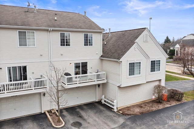 back of property featuring an attached garage, roof with shingles, and aphalt driveway