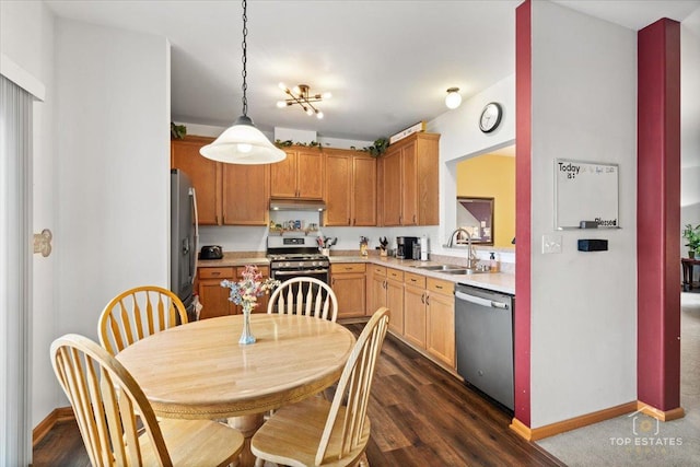kitchen featuring a sink, light countertops, appliances with stainless steel finishes, under cabinet range hood, and dark wood-type flooring