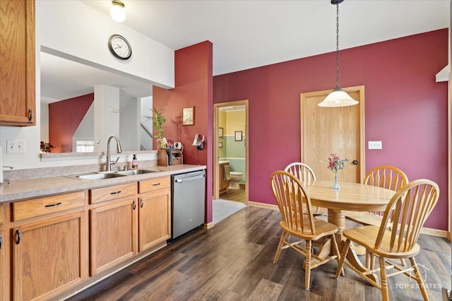 kitchen with dark wood-type flooring, dishwasher, a sink, light countertops, and decorative light fixtures