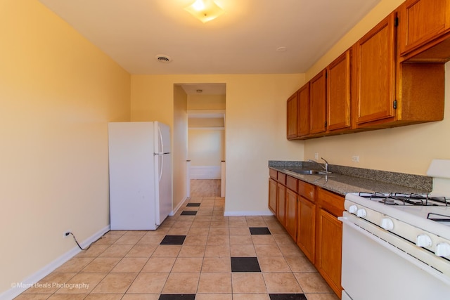 kitchen with white appliances, visible vents, brown cabinets, and a sink