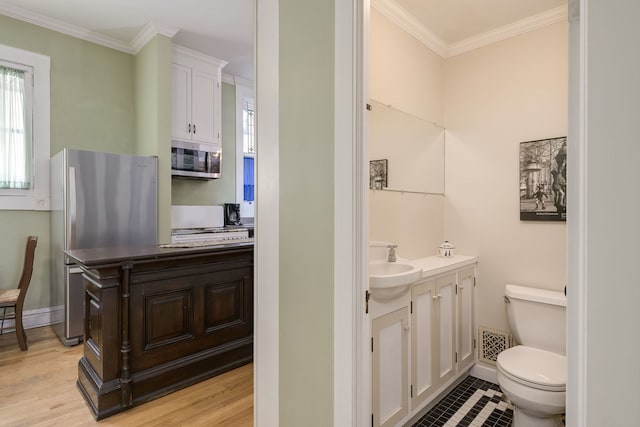 half bath featuring vanity, ornamental molding, visible vents, toilet, and wood finished floors