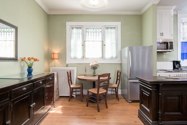 dining area with crown molding and light wood finished floors