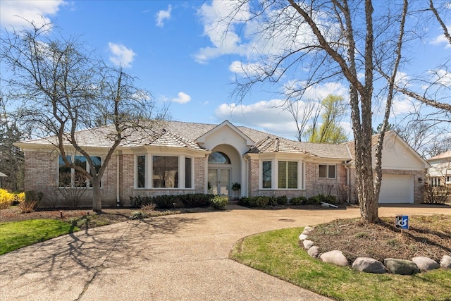 single story home with brick siding, french doors, an attached garage, and concrete driveway