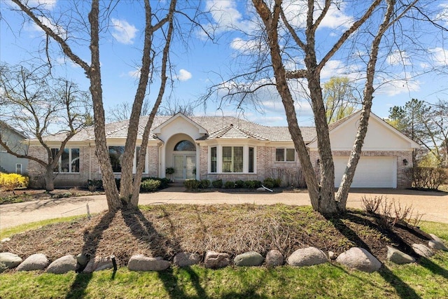 single story home with driveway, french doors, a garage, stucco siding, and brick siding