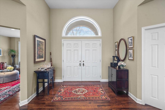 foyer entrance with a high ceiling, dark wood-style flooring, and baseboards