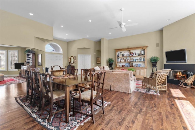 dining room with a ceiling fan, a glass covered fireplace, recessed lighting, and dark wood finished floors