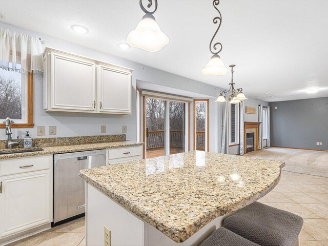 2072 Charnwood Ct, Machesney Park, IL 61115 - kitchen with stainless steel dishwasher, light stone counters, a tiled fireplace, a sink, and hanging light fixtures