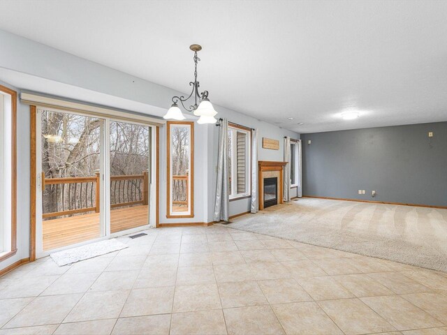 2072 Charnwood Ct, Machesney Park, IL 61115 - unfurnished living room featuring visible vents, baseboards, a chandelier, light tile patterned flooring, and a glass covered fireplace