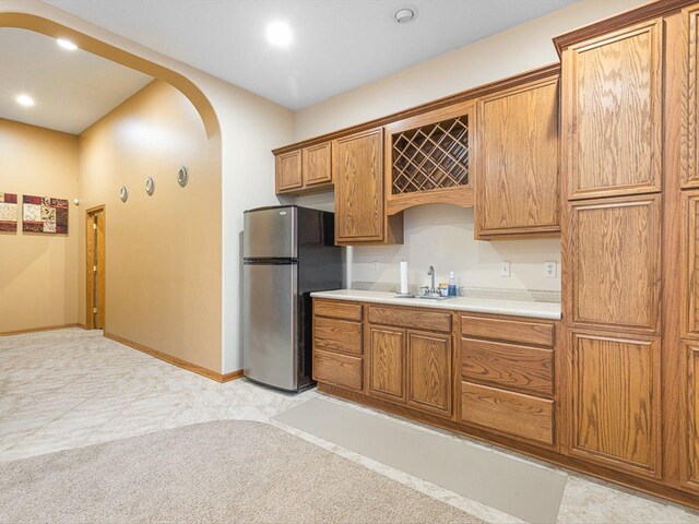 2072 Charnwood Ct, Machesney Park, IL 61115 - kitchen featuring arched walkways, a sink, light countertops, freestanding refrigerator, and brown cabinets