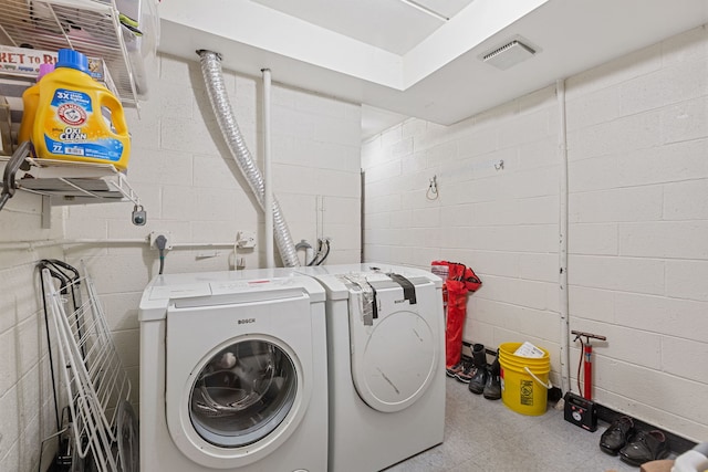 washroom featuring laundry area, separate washer and dryer, visible vents, concrete block wall, and tile patterned floors