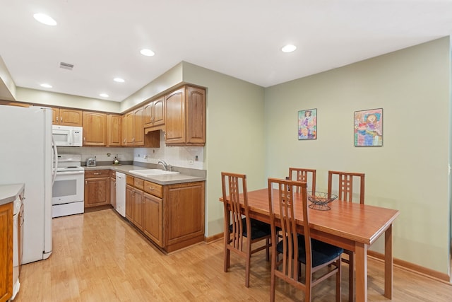 kitchen with white appliances, visible vents, light wood-type flooring, and a sink
