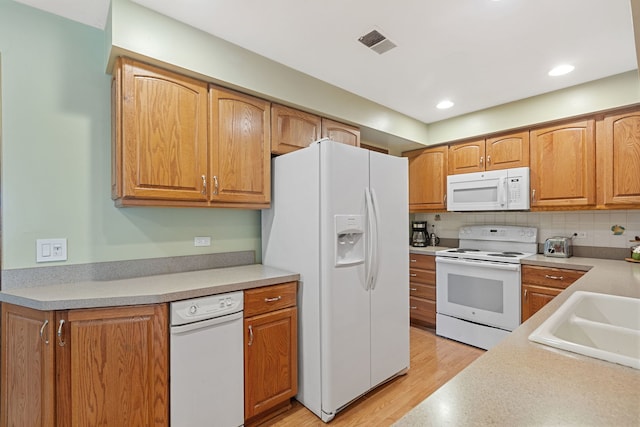 kitchen featuring white appliances, light wood-style flooring, light countertops, visible vents, and a sink