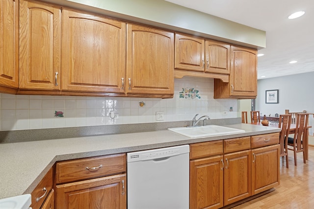 kitchen with light wood-type flooring, recessed lighting, dishwasher, a sink, and backsplash