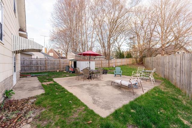 view of yard with a storage shed, a fenced backyard, an outdoor structure, and a patio