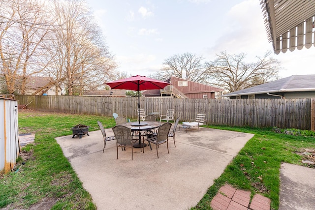 view of patio featuring outdoor dining space, a fenced backyard, and a fire pit