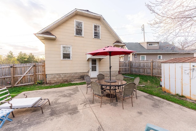 rear view of house featuring a patio area, a fenced backyard, outdoor dining area, a storage unit, and an outbuilding