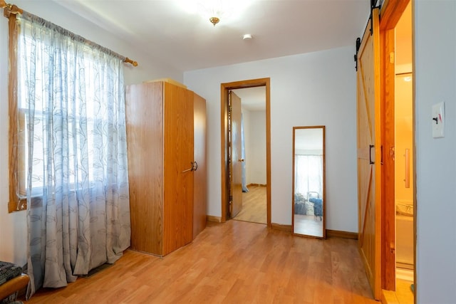 interior space with light wood finished floors and a barn door